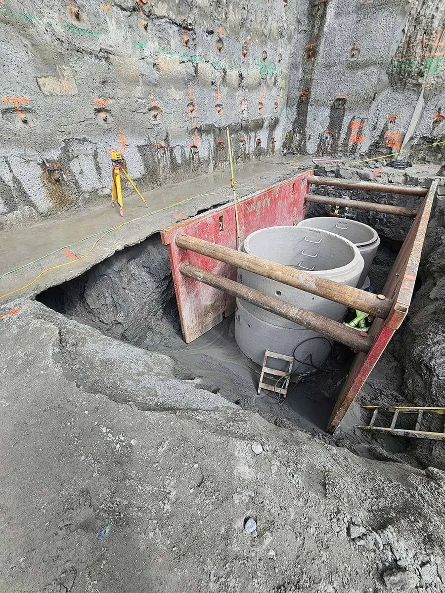 Manhole sections set inside a trench box at the bottom of the excavation