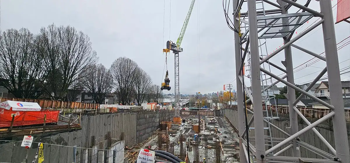 Compact excavator being lowered into the excavation by crane