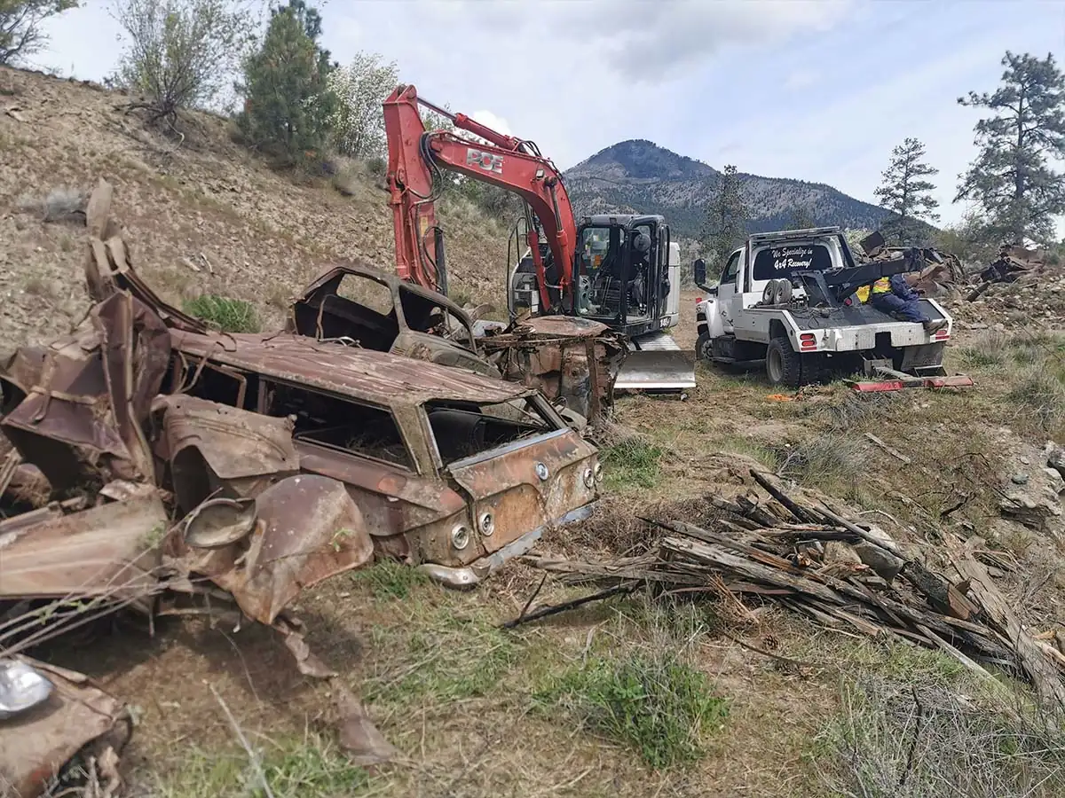 Excavator and trucks with recovered wrecks on the slope