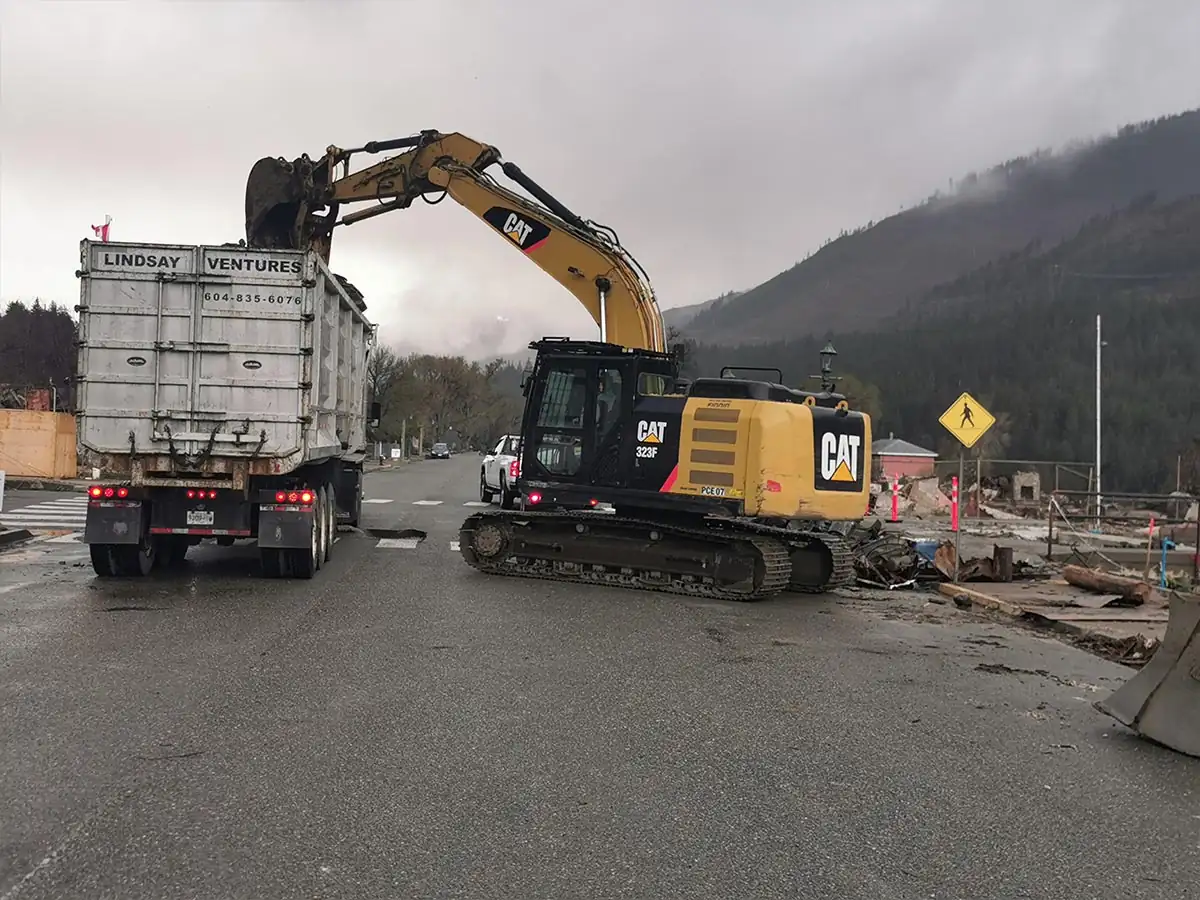 Excavator loading a disposal truck on the highway through Lytton