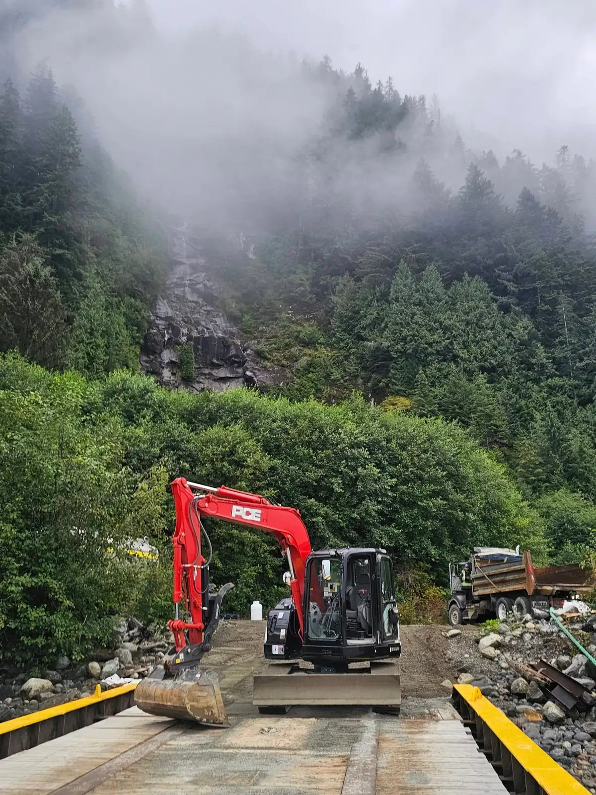Compact red PCE excavator on the barge ramp