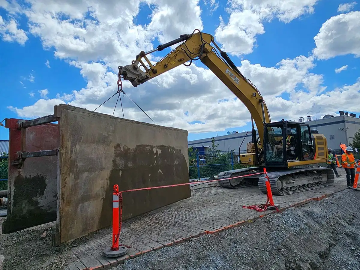 Excavator moving a trench shield panel