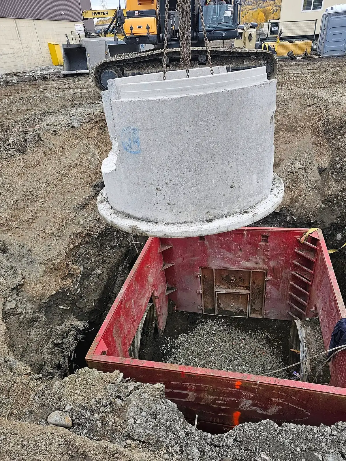 Manhole barrel set into place in the shoring box